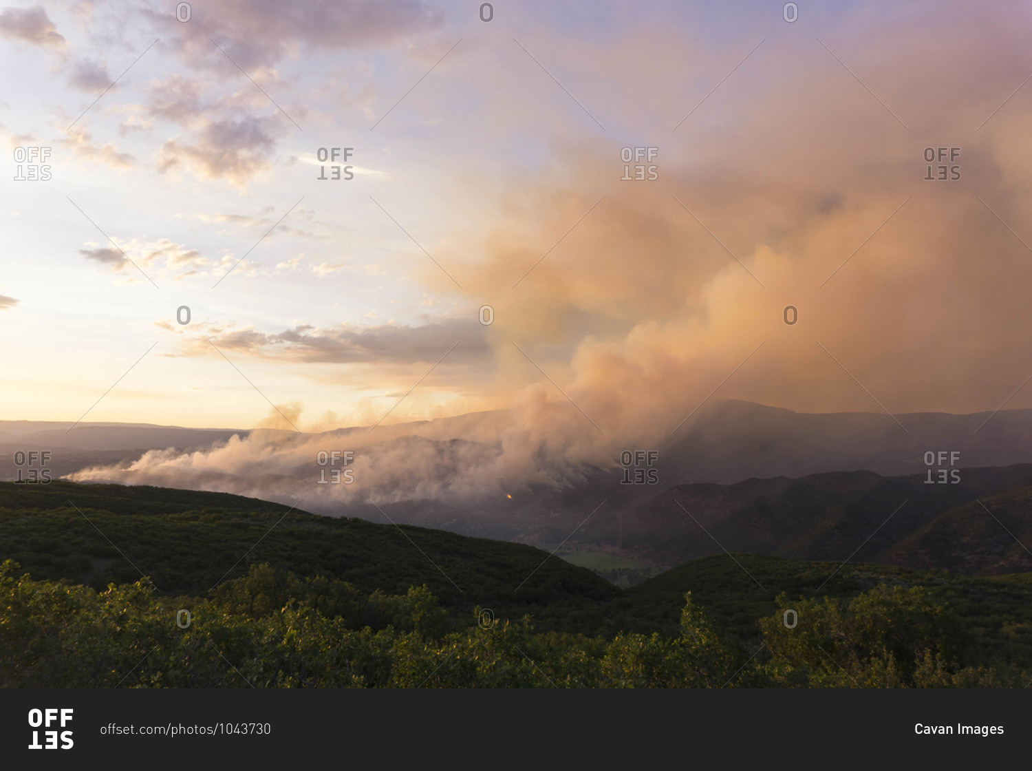 Smoke emitting from wildfire on mountain against sky