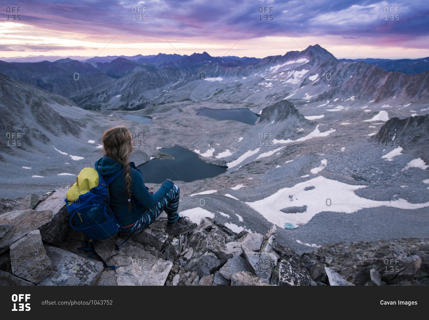 Female hiker looking at mountains while sitting on rocks during sunset