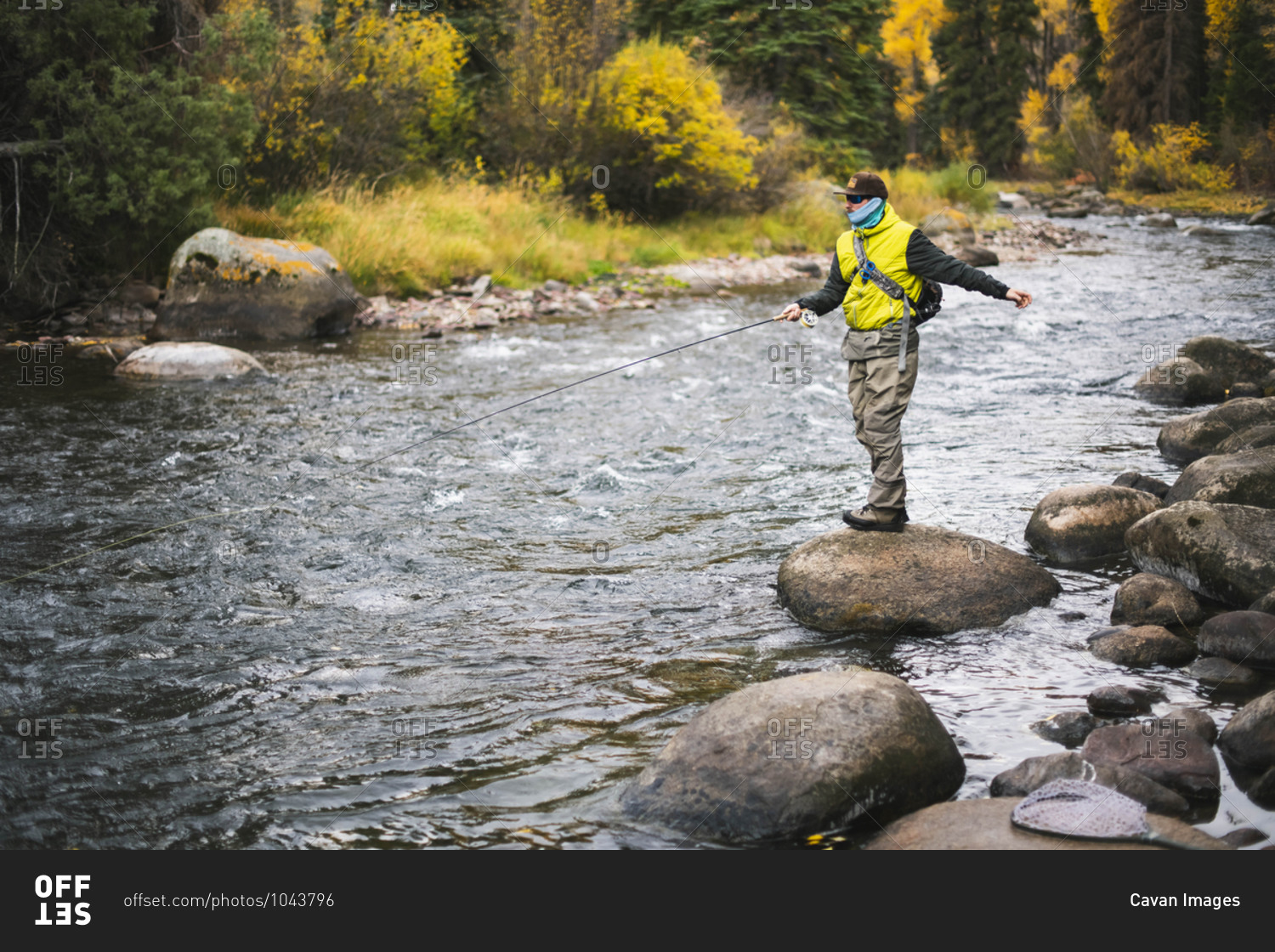 Man fly fishing while standing on rock at Roaring Fork River during autumn