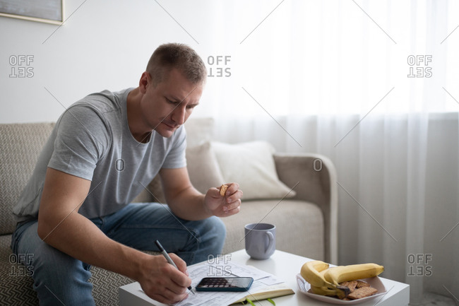 Adult man snacking and doing paperwork