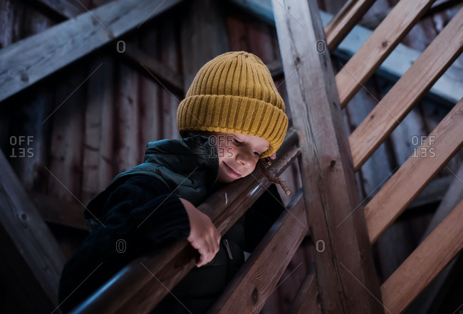 Young boy on a wooden stairway looking down through beautiful light