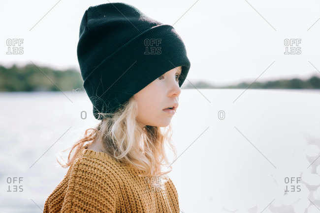 Close up portrait of a young girl with a beanie on looking out to sea