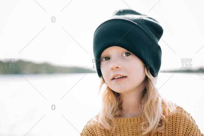 Portrait of a young girl stood at the beach with a beanie on