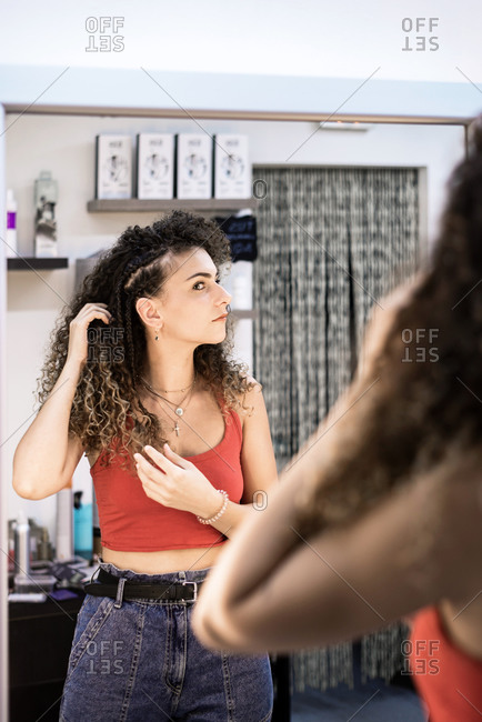Satisfied girl customer looking at herself on the mirror at hairdresser salon