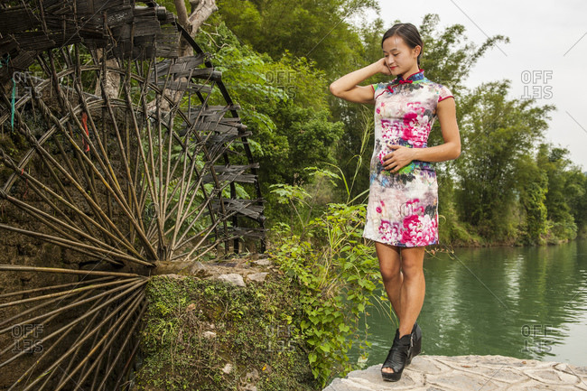 Beautiful woman standing next to water mill in Yangshuo