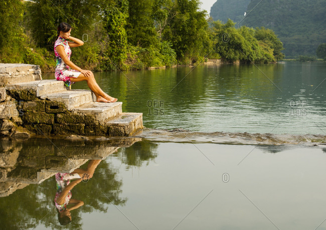 Beautiful woman sitting next to the river Li in Yangshuo