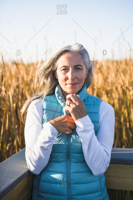 Gray Haired Woman enjoying a nature walk in golden marsh