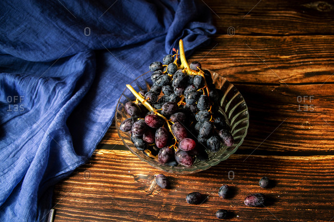 Black grapes inside a glass bowl on a wooden table