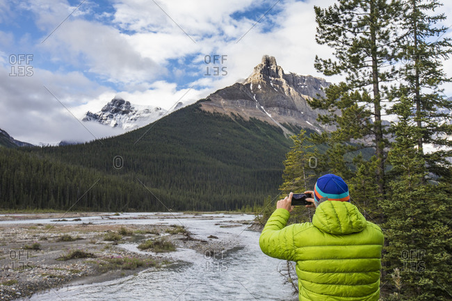 Man in green jacket takes a photo of Alexandra Mountain, Banff, Canada