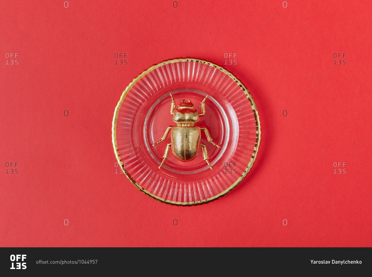 Close-up composition from golden scarab bug made from gold metal on vintage glass plate on a coral background with copy space. Egyptian Scarab. Top view.