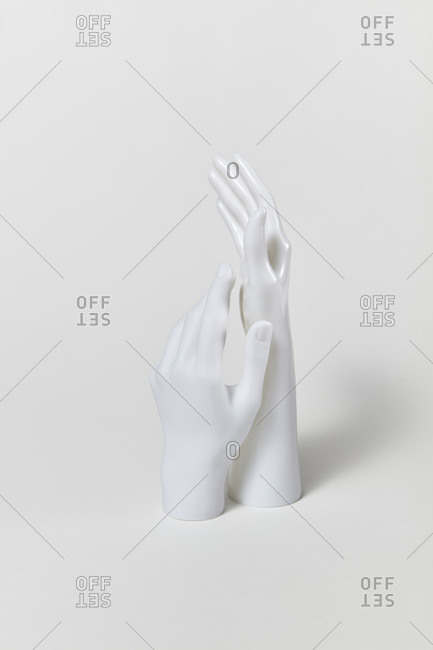 Two white artificial plastic mannequin hands raised up on a light grey background, copy space. Concept of vote and agree.