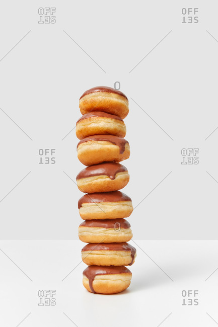 Food vertical pyramid from delicious homemade glazed chocolate doughnuts on a light gray background, copy space.