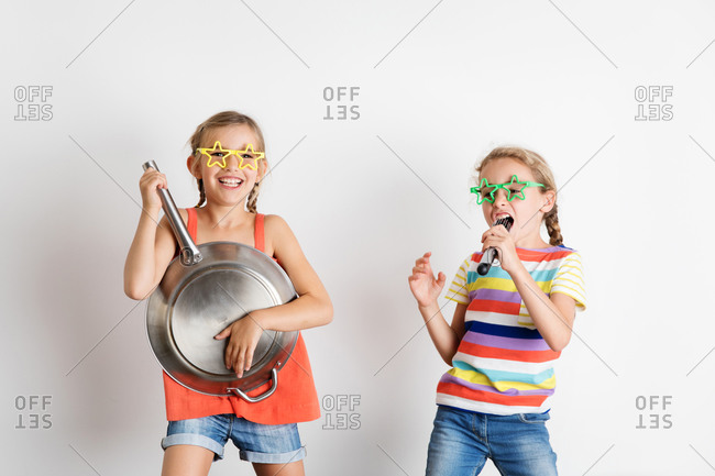 Portrait of happy little girls pretending to sing and play music