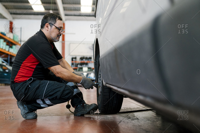 Auto mechanic adjusting car tire in workshop