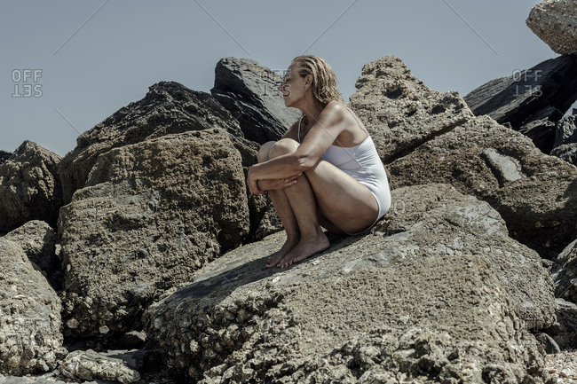 Little girl in underwear on rocky beach stock photo - OFFSET