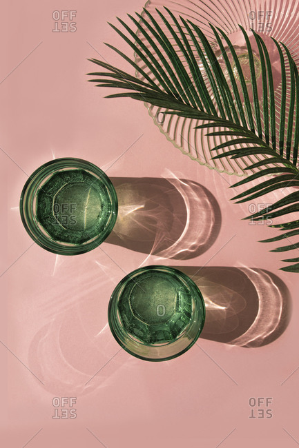 Studio shot of palm leaves- glass bowl and two glasses of carbonated water