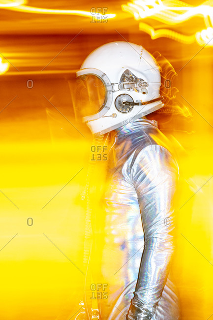 Mid adult man wearing space suit standing amidst abstract light
