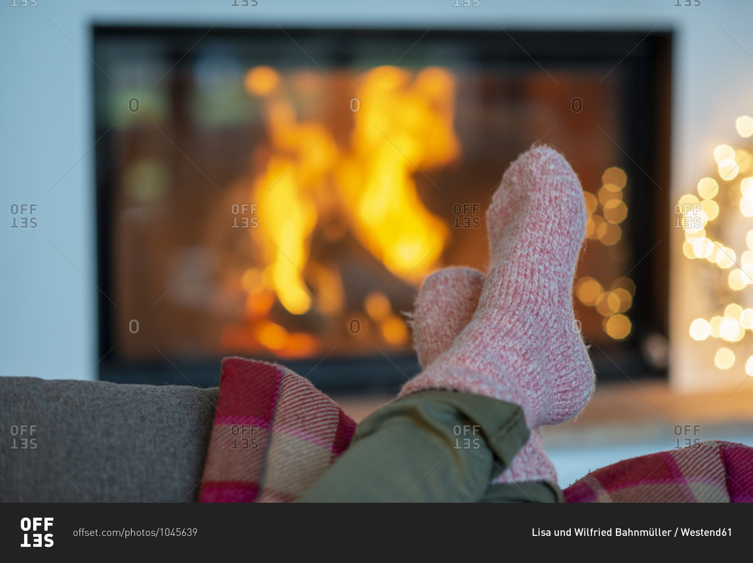 Legs of young woman wearing socks relaxing against fireplace at home