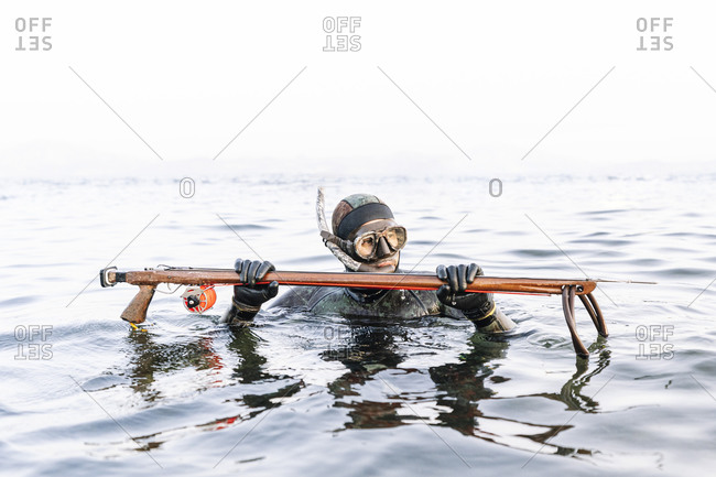Man hunting with harpoon in sea against clear sky