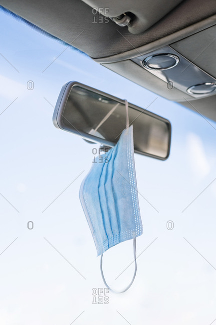 Close-up of face mask hanging on rear-view mirror in car