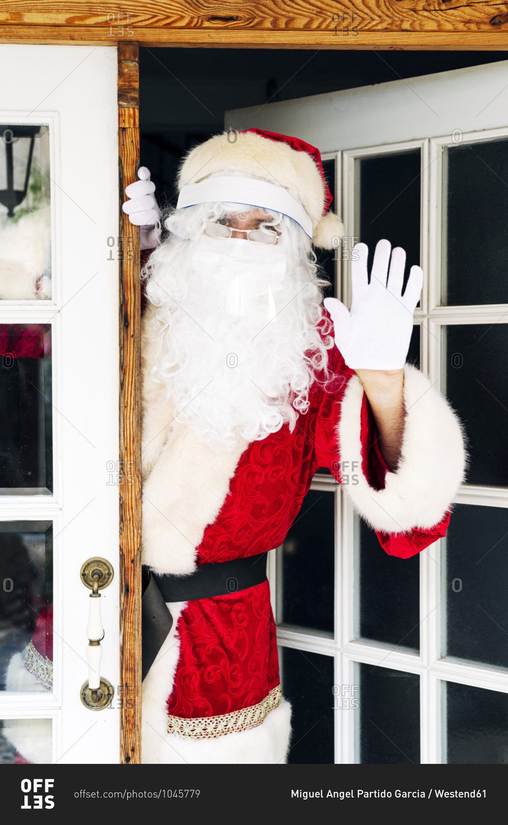 Man wearing Santa Claus costume showing stop sign while standing at entrance of house