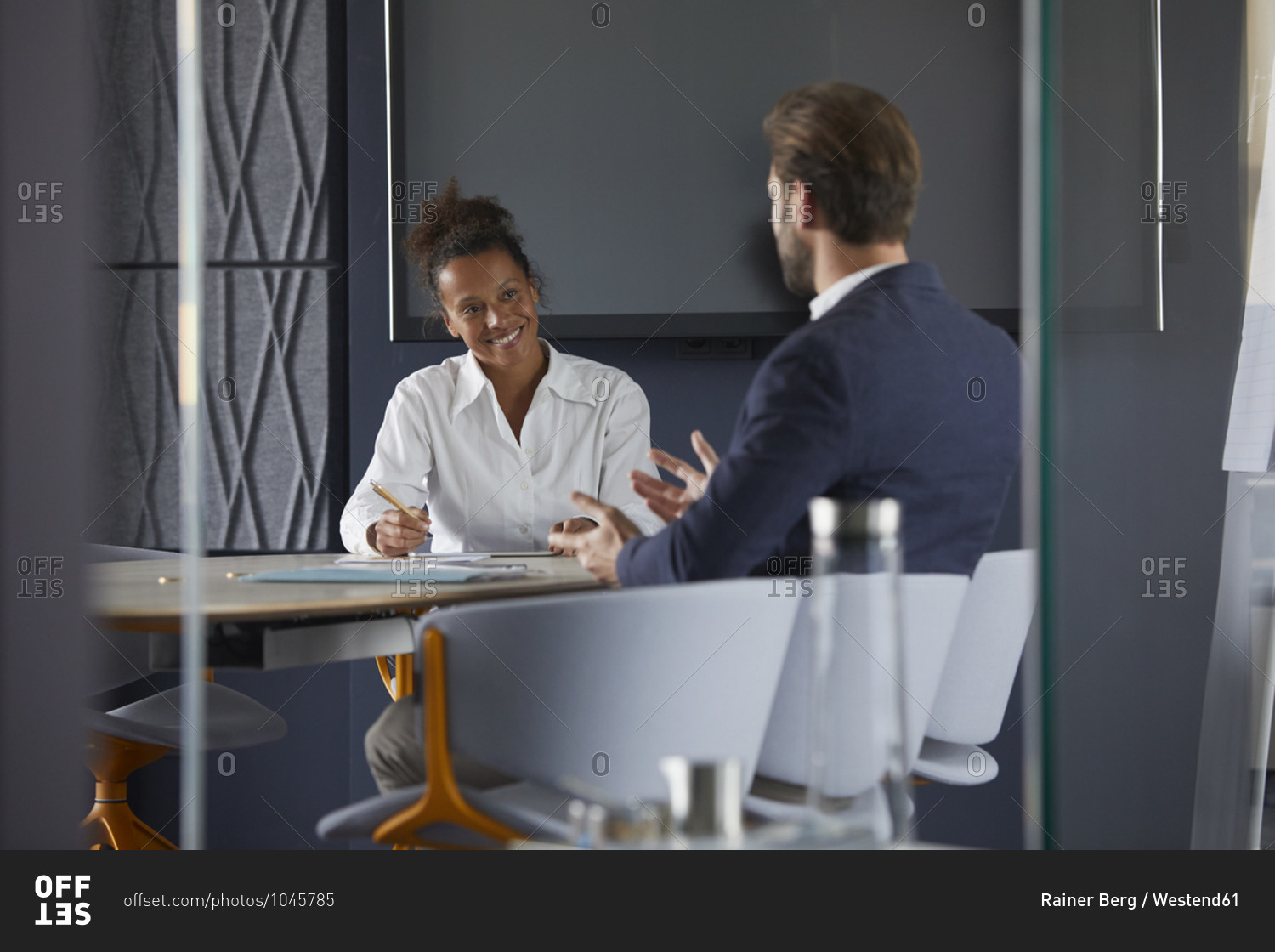 Businessman and colleague discussing while sitting in office