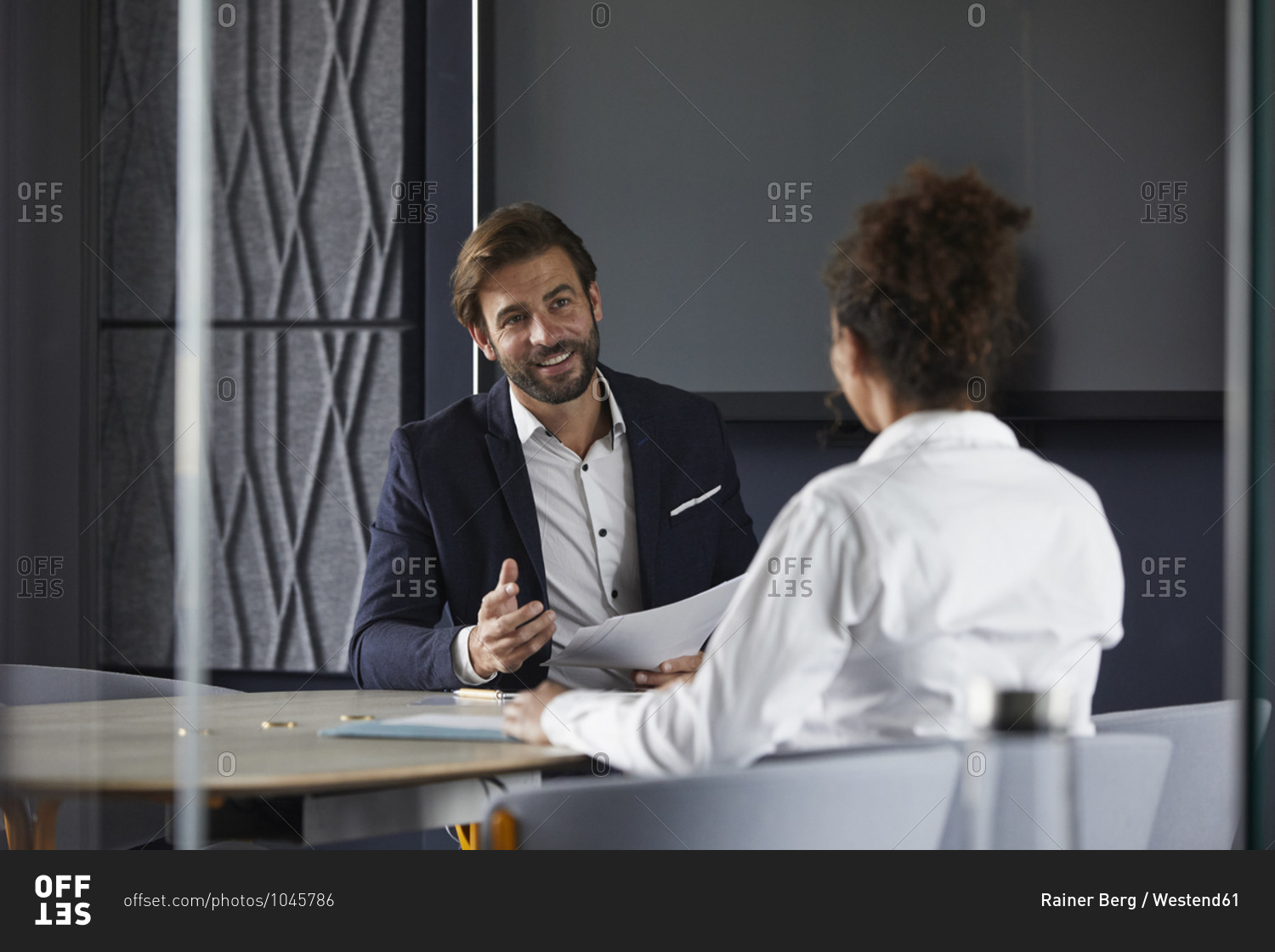 Smiling businessman discussing with colleague in meeting at office