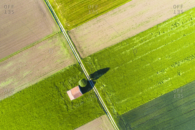 Drone view of dirt road stretching between countryside fields in spring