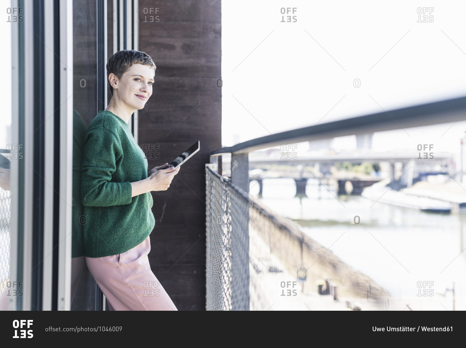 Thoughtful female professional with digital tablet standing in balcony at office