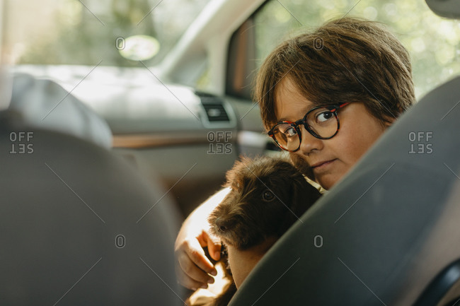 Boy sitting with puppy in car