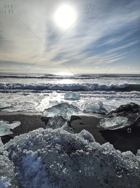 Bizarre ice formations were touched on the black sand beach of diamond beach, iceland
