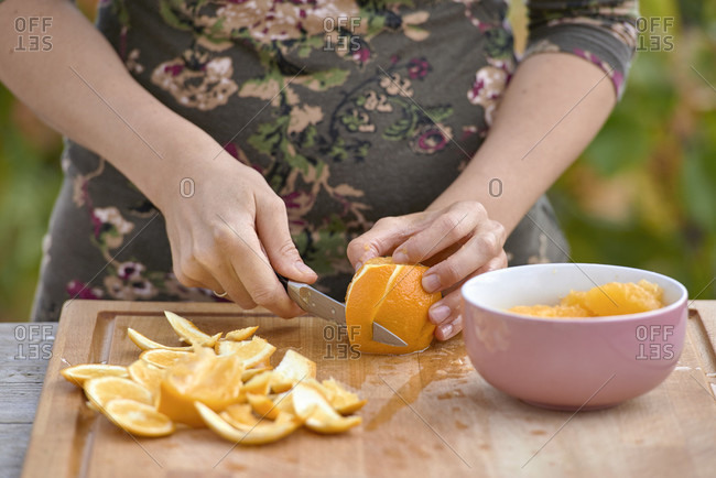 Female hands fillet orange on wooden board