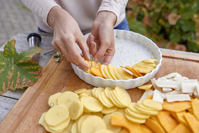 Prepare a gratin of potatoes, pumpkin and jerusalem artichoke, arrange the sliced ingredients in a buttered baking pan