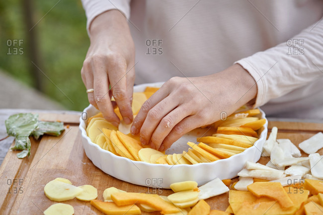 Prepare a gratin of potatoes, pumpkin and jerusalem artichoke, arrange the sliced ingredients in a buttered baking pan