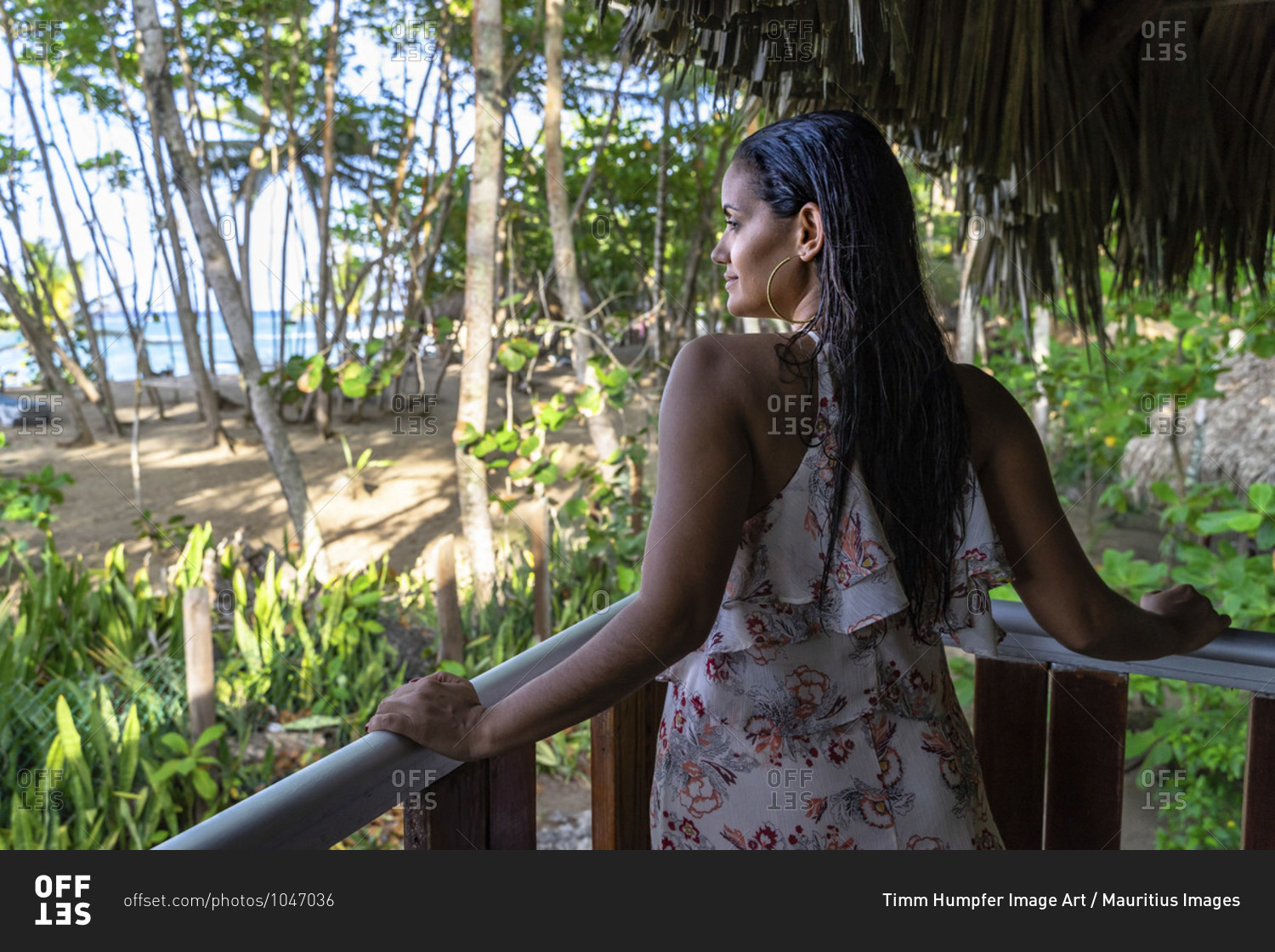 America, caribbean, greater antilles, dominican republic, cabarete, woman looks out from a balcony onto the beach at the natura cabana boutique hotel & spa