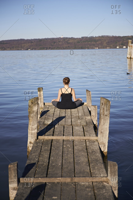 Meditation at the Ammersee, woman sitting on jetty, blue sky