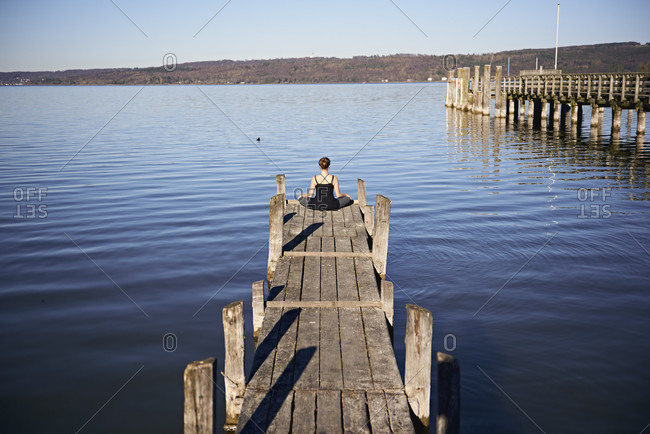 Meditation at the Ammersee, woman sitting on jetty, blue sky