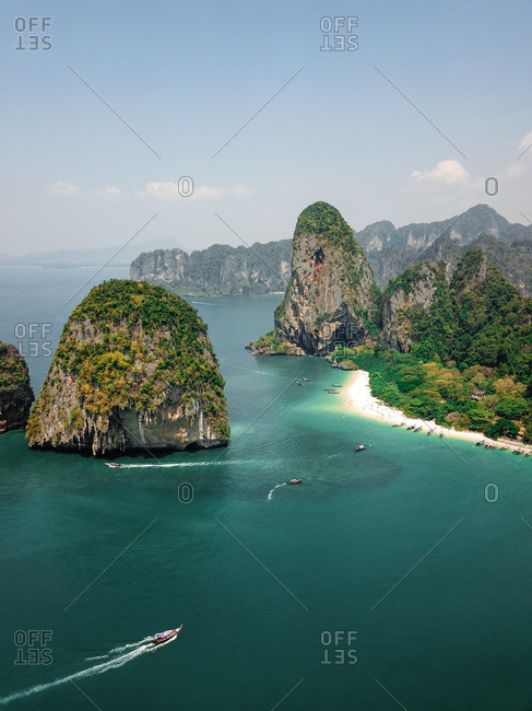 Aerial view of tiny speed boats exploring the giant limestone cliffs and islands in the turquoise blue sea, a tropical paradise, Phra Nang, Krabi, Phuket, Thailand.