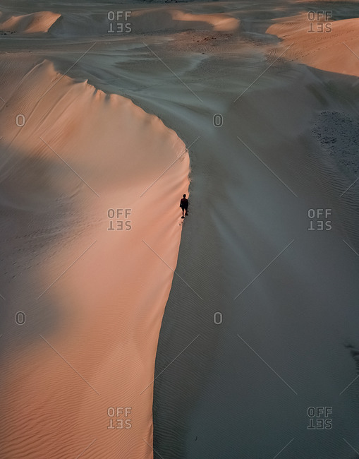 Aerial view of person walking on sand with pink sunset sunrise on Lancelin Sand Dunes, Western Australia