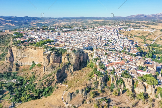 Aerial view of a cliffside mountaintop city with the stone bridge "Puente Nuevo" and the Plaza de Toros in Ronda, Andalusia, Spain.