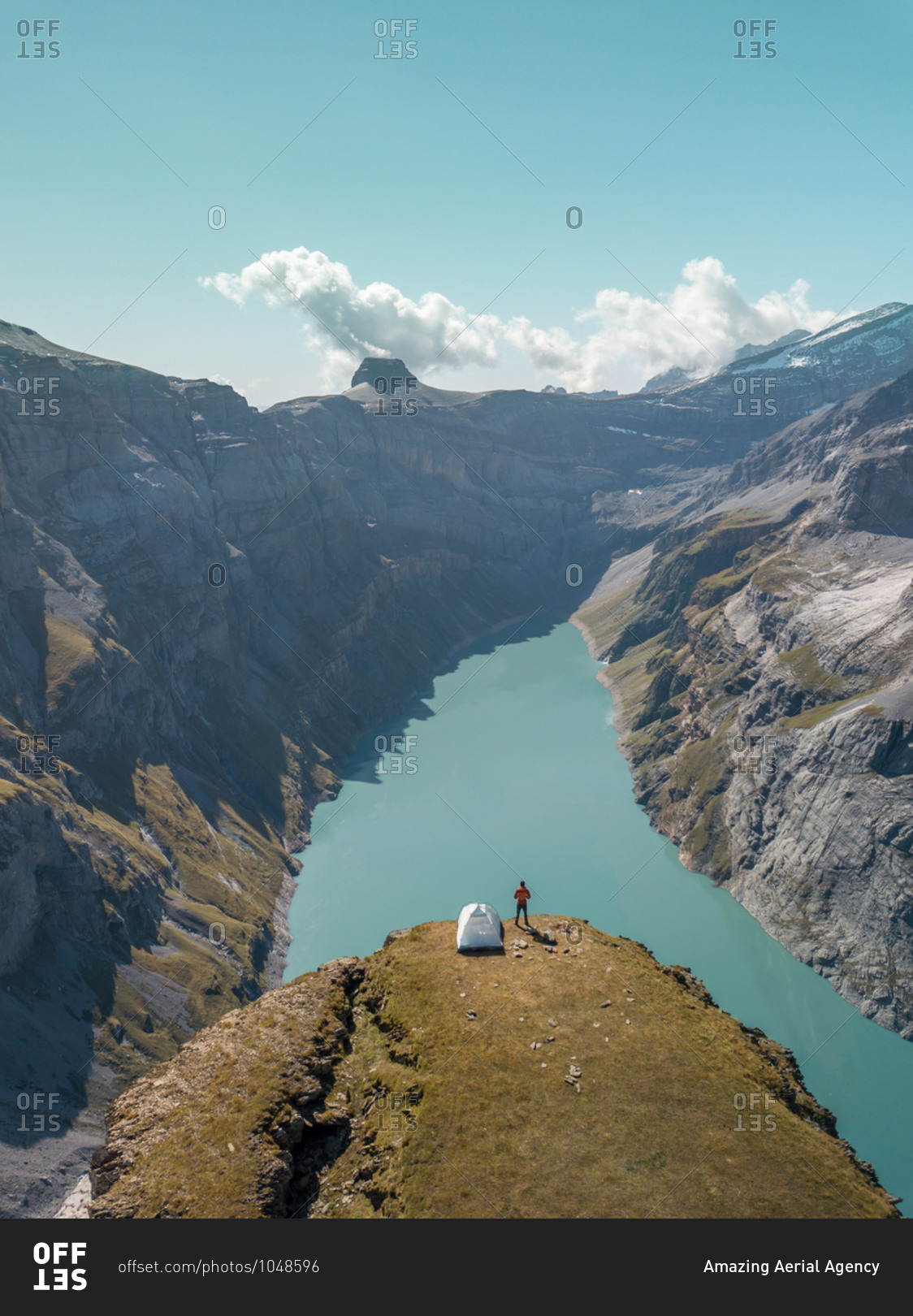 Aerial View of hiker with tent admiring view od Swiss Mountain Lake in Glarus, Switzerland.