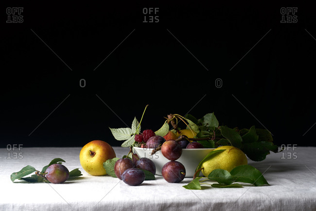 Still life with fresh organic fruits from the garden: plums, pears and apples on white textile background