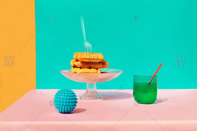 Low angle view of waffle- juice- rubber ball and multi colored napkin kept on table