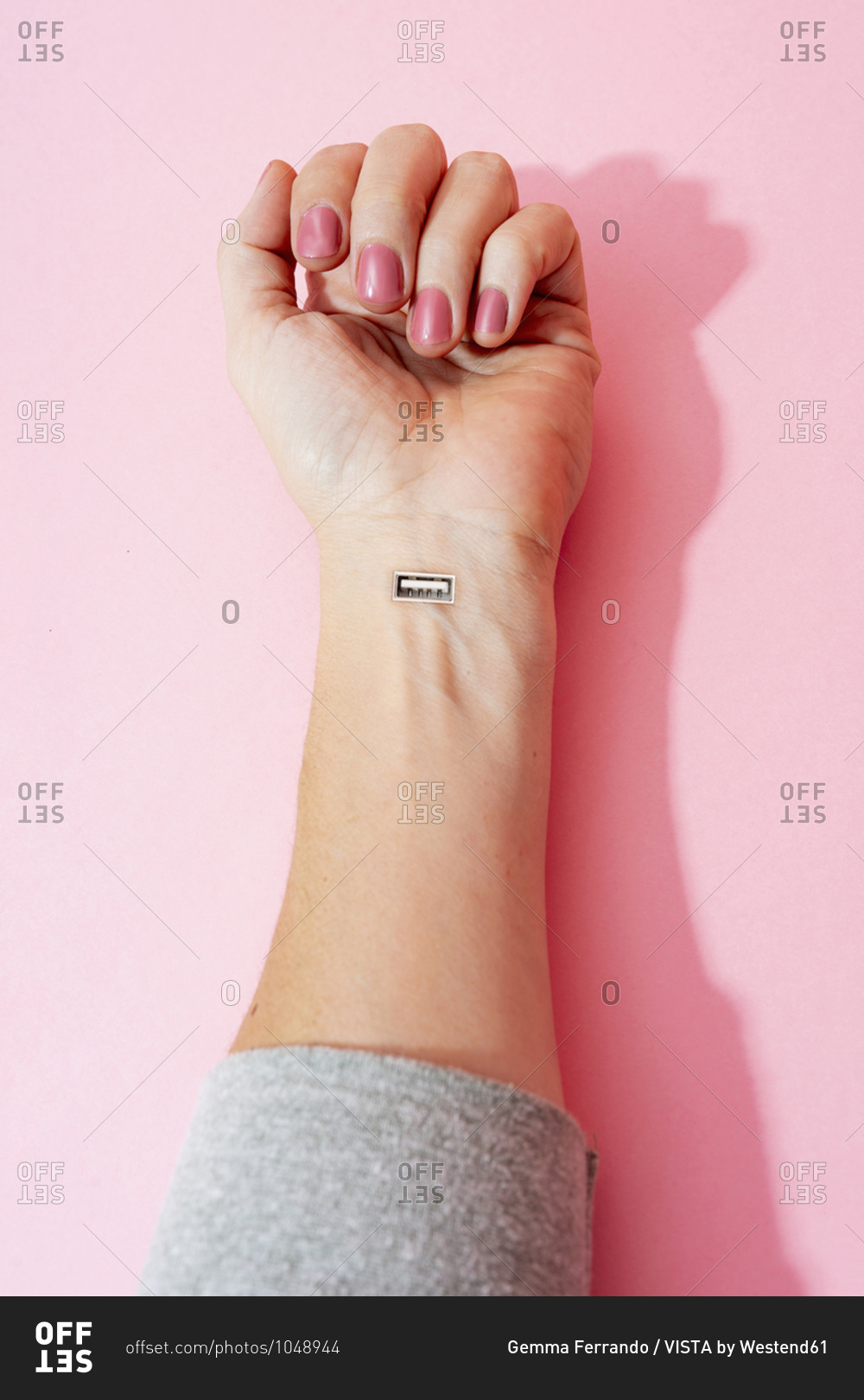 Cropped image of female hand with nail polish and USB port against pink wall