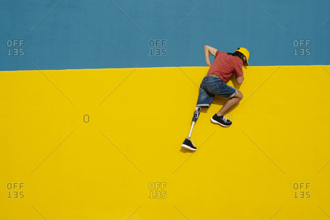 Disabled athlete putting efforts to climb multi colored wall