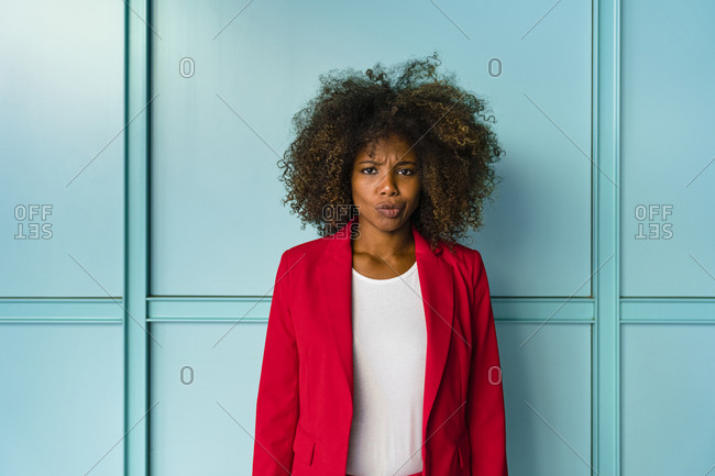 Woman making facial expression while standing against blue background