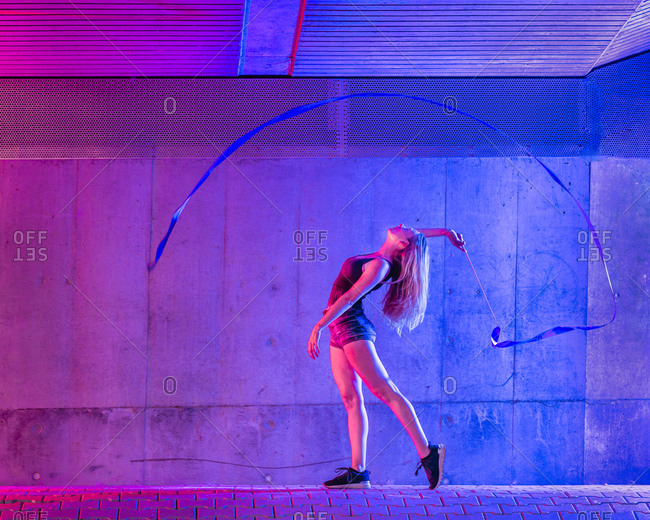 Young woman spinning ribbon while standing against wall