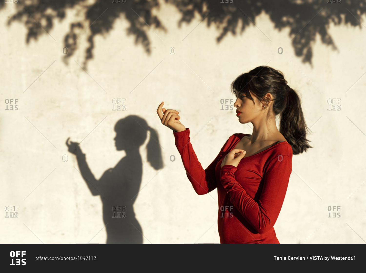 Contemplating woman doing hand gesture while standing by tree shadow