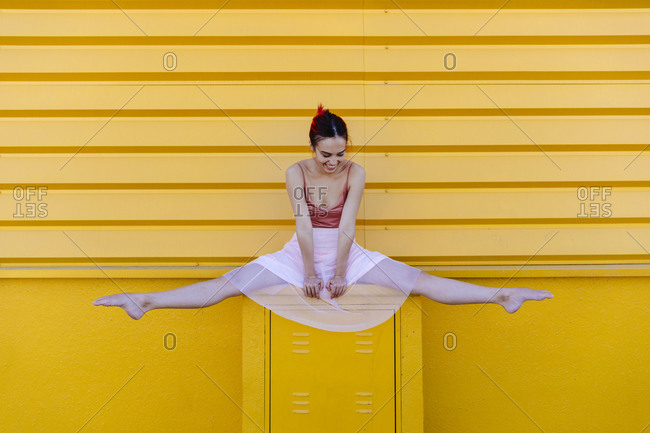 Woman in sportswear doing side leg split on a wall outdoors stock photo -  OFFSET