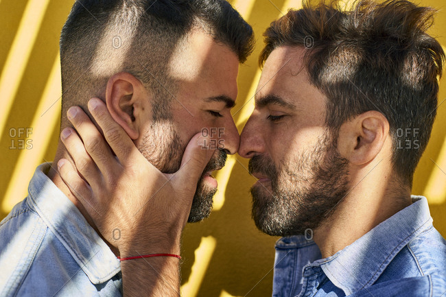 Gay couple standing face to face against yellow wall